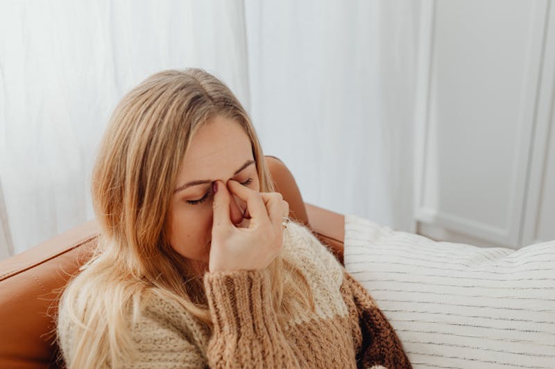 Woman pressing nose bridge due to sinus pressure from a head cold