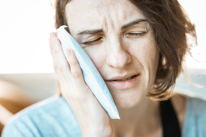 Woman applying a warm compress to relieve ear pressure from a cold