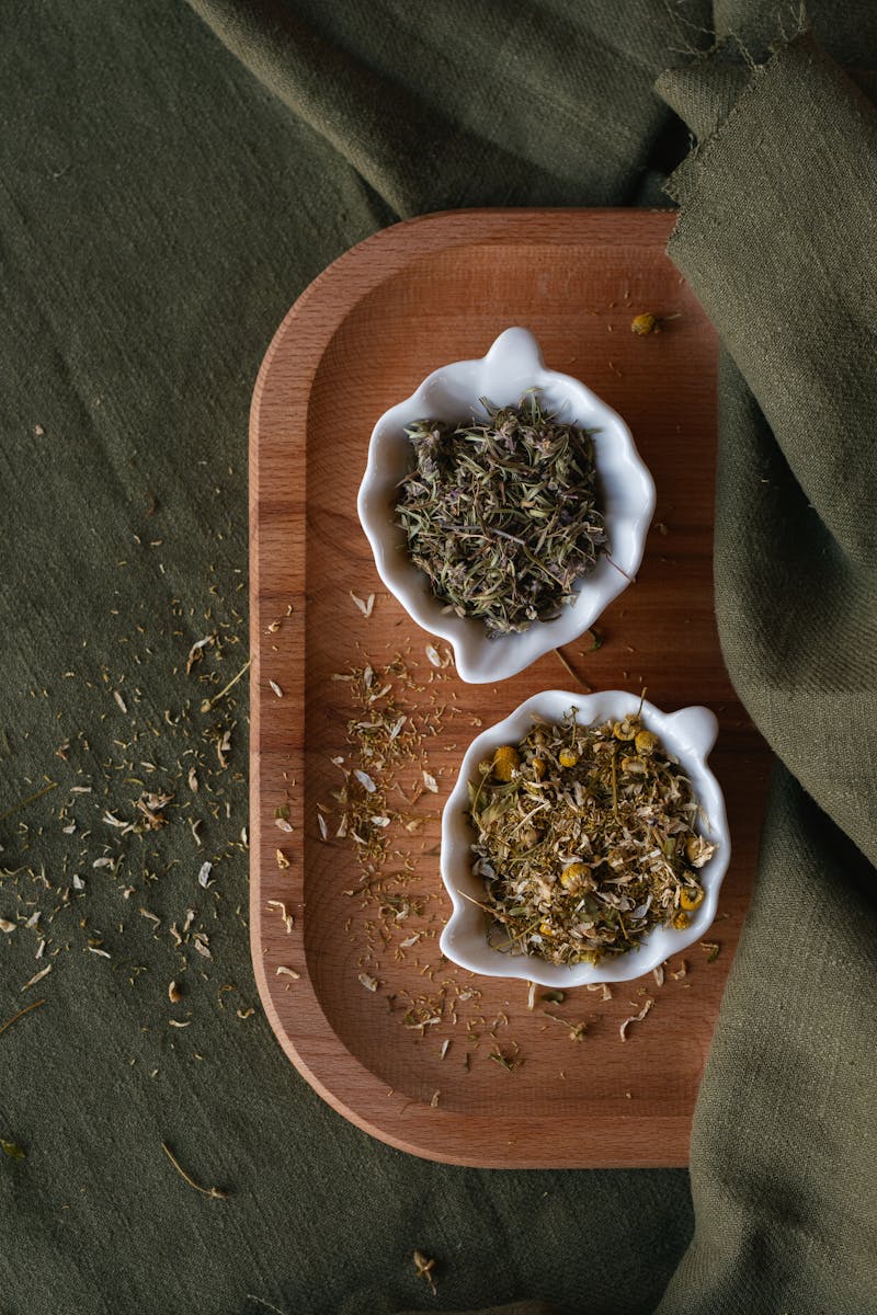 Dried herbal tea blends in ceramic bowls on a wooden tray — natural cold remedies
