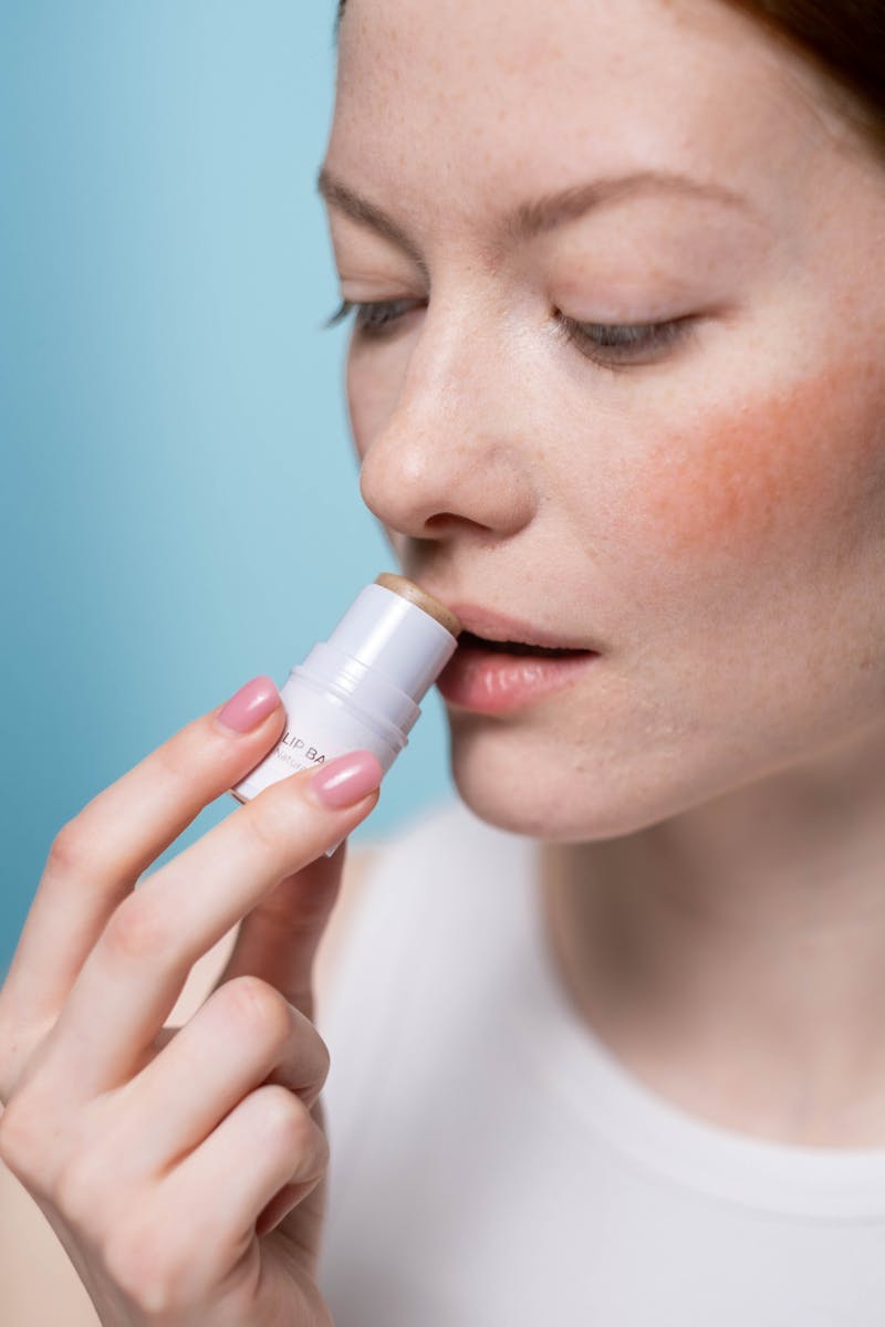 Woman applying lip balm treatment — protecting and healing lips from cold sores