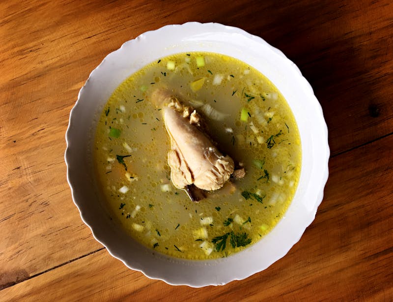 Homemade chicken soup in a white bowl with herbs — a research-backed cold remedy